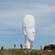 Guests hiking and taking selfies in a rugged natural setting with a large sculpture of a woman's head